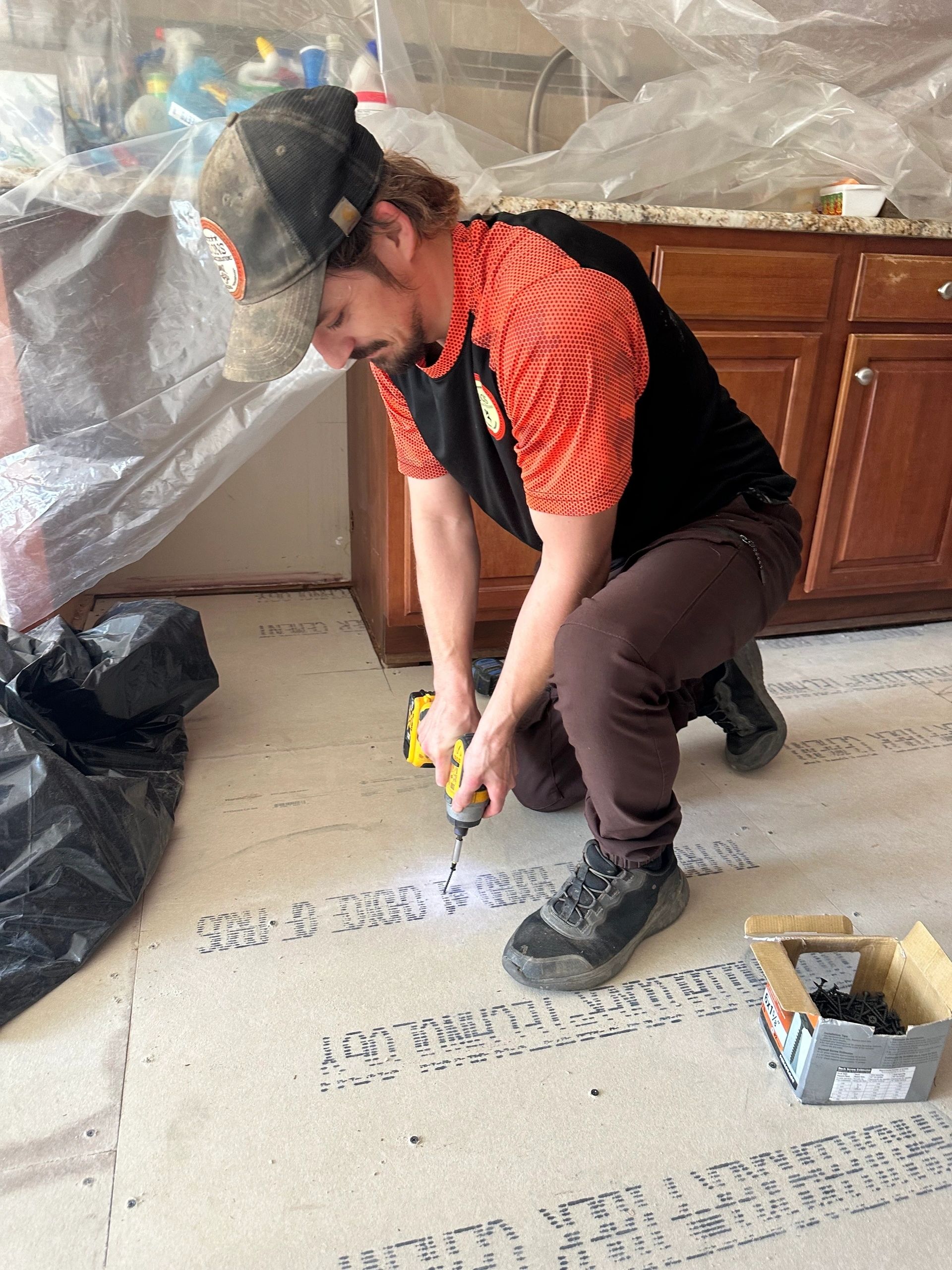Driving a screw home with a cordless driver, down on one knee.
