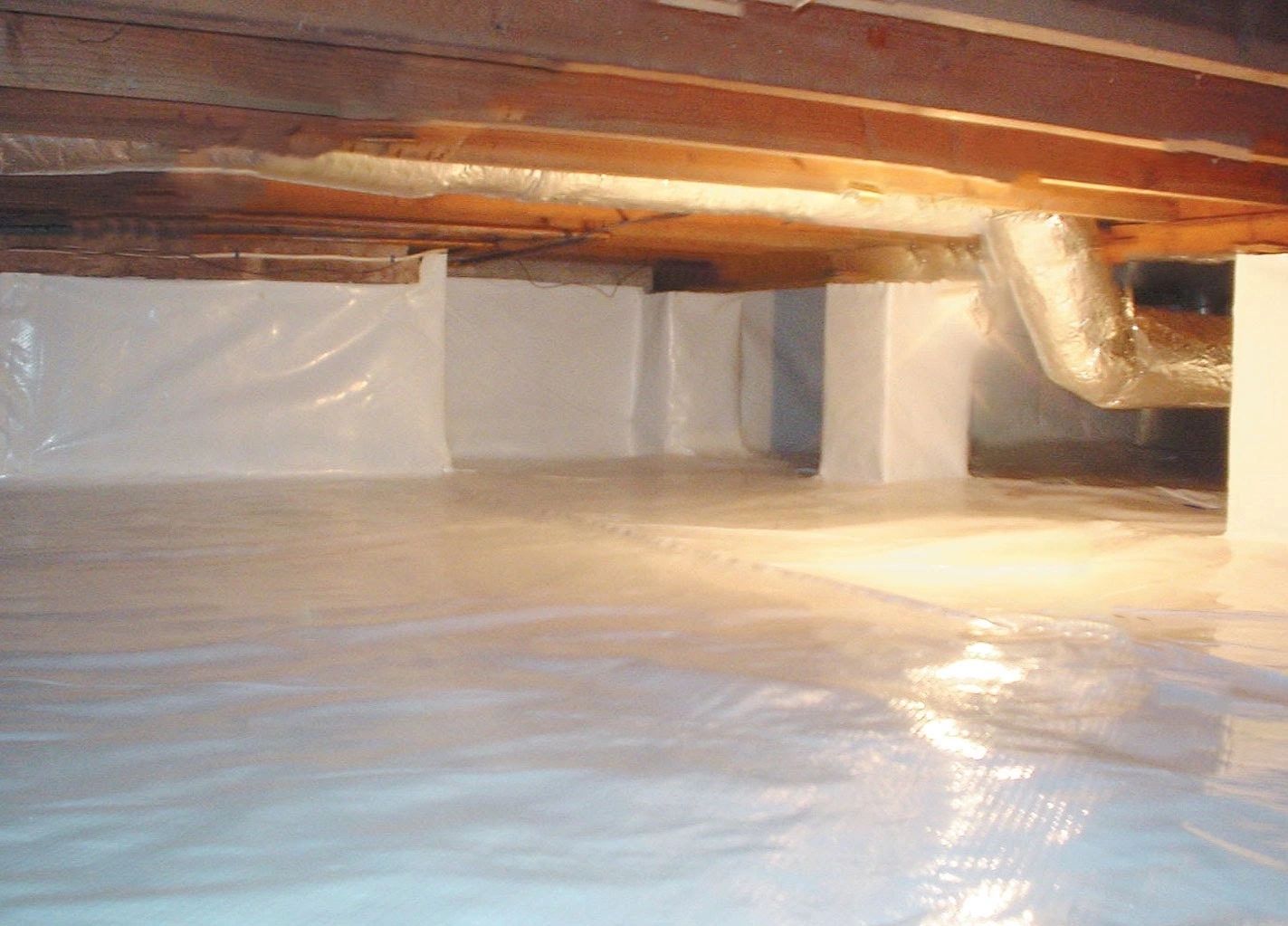 A sealed crawl space with the piers wrapped and the joists open above.