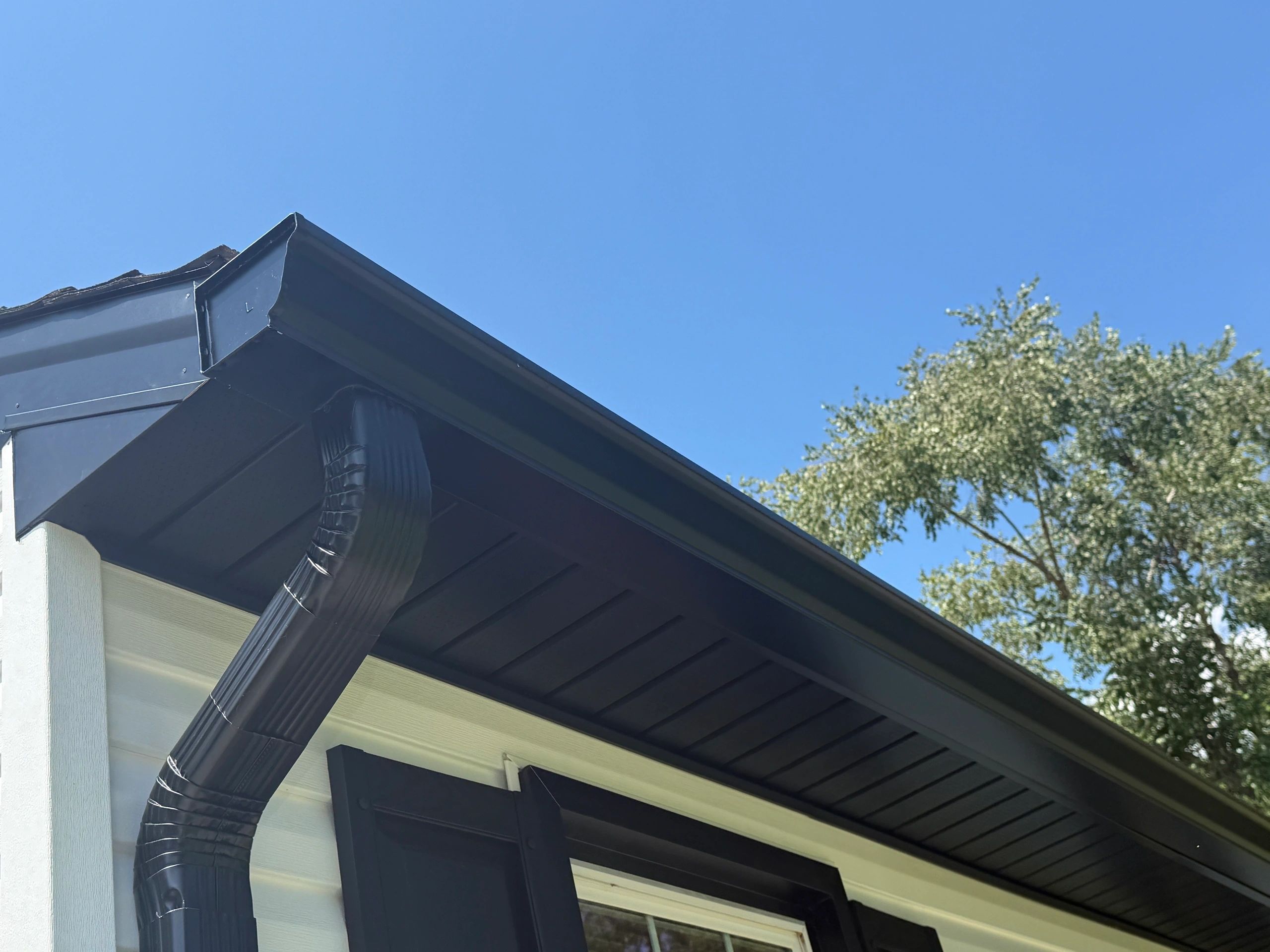 Seamless black gutter run along a white fascia against the sky.